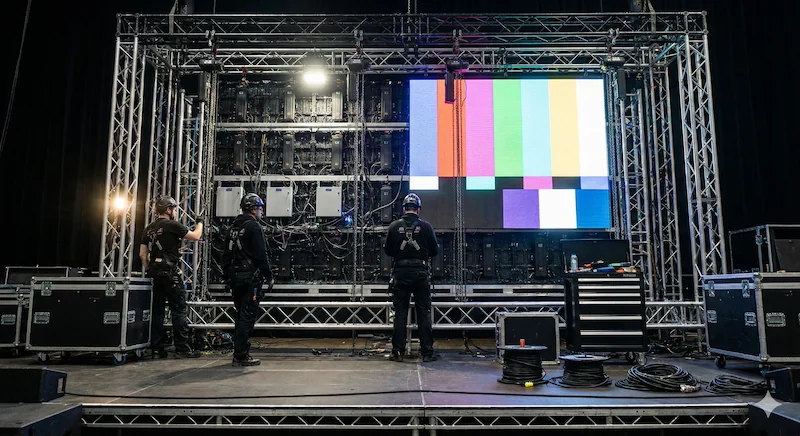 Técnicos audiovisuales ensamblando la estructura trasera y el cableado de un diseño de pantallas led gigantes para eventos.